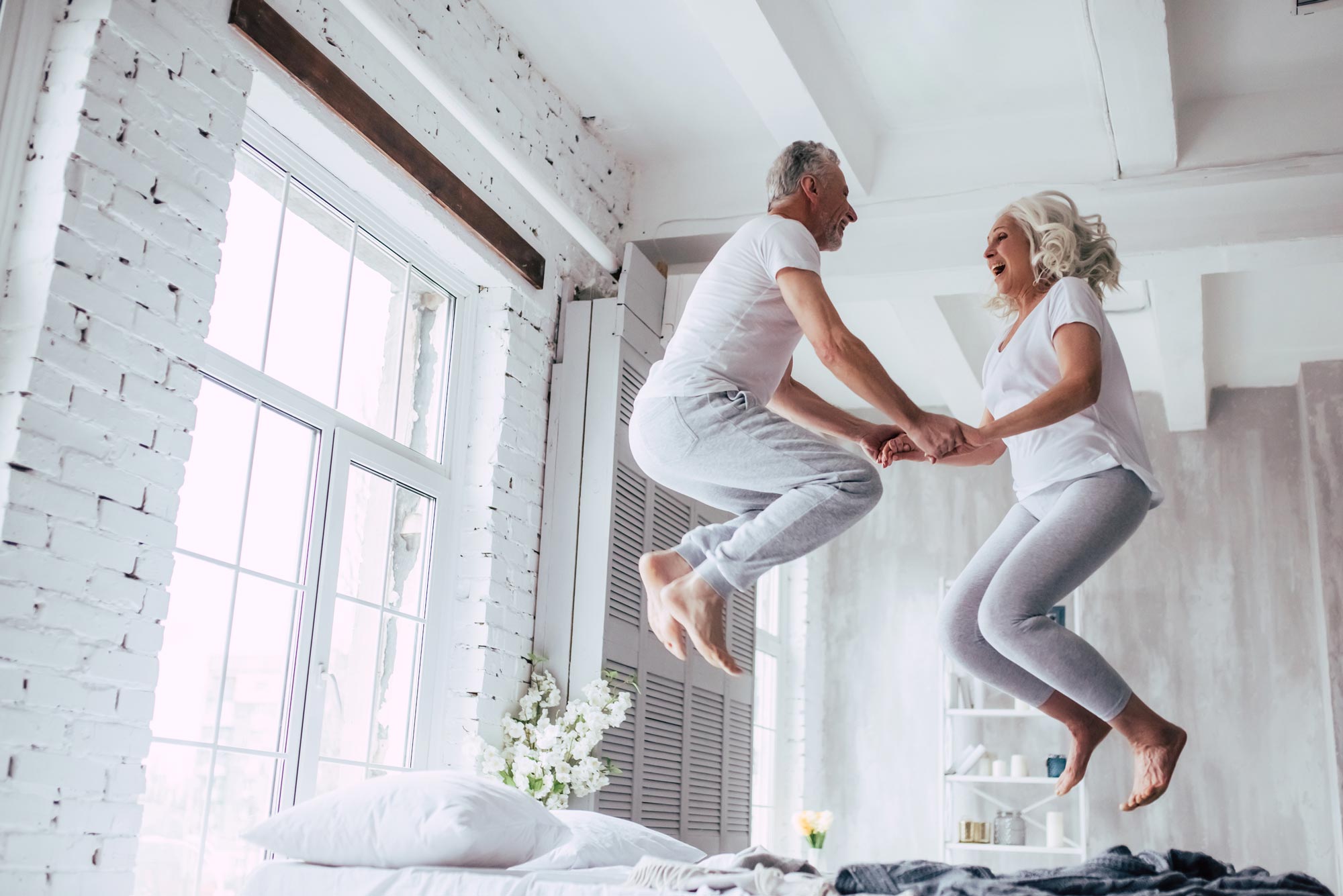Retired couple jumping on bed