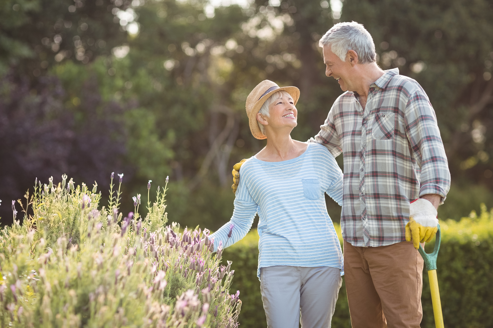 Retired couple smiling at each other while gardening