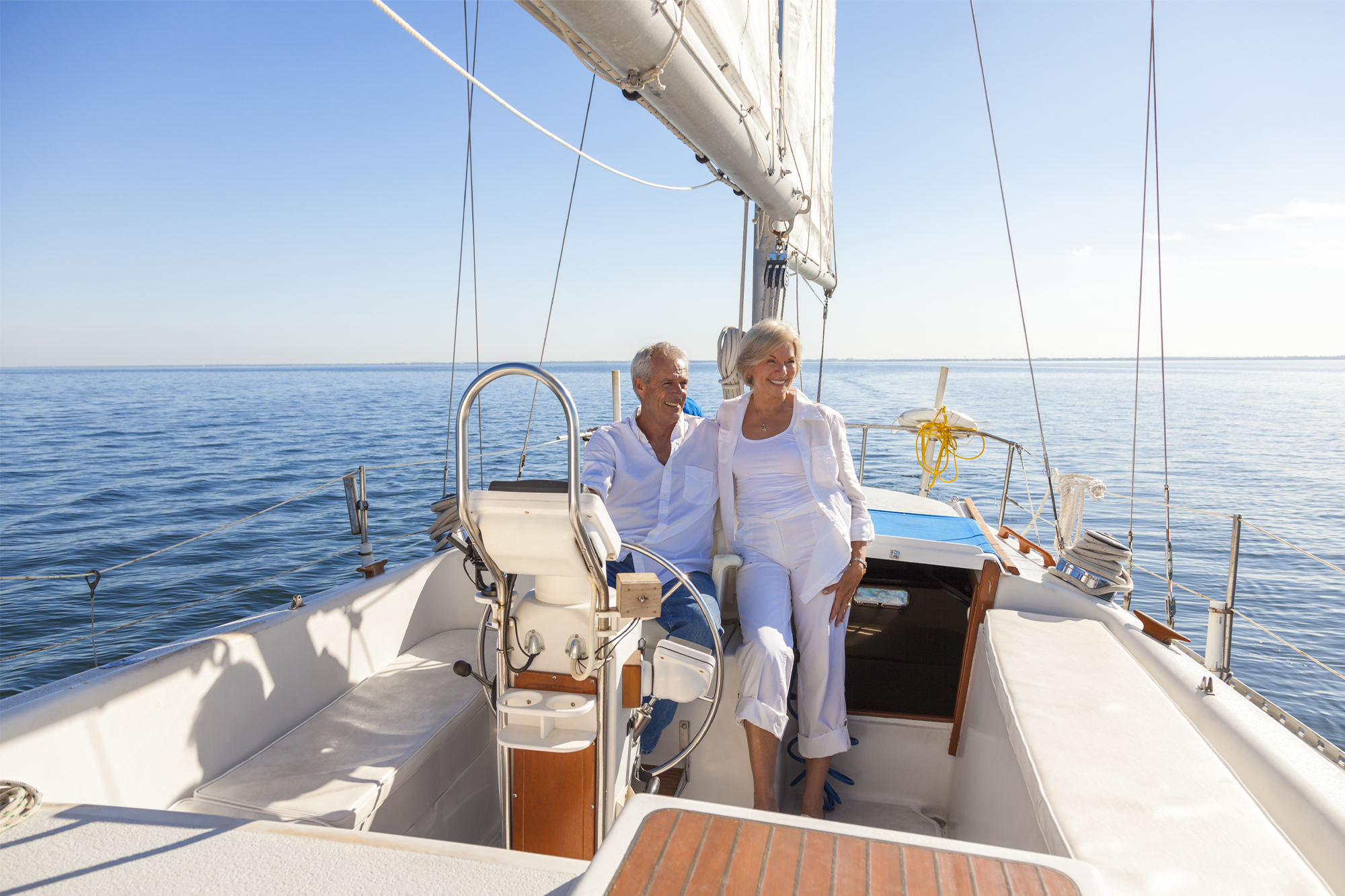 Retired couple smiling on a sailboat